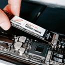 M12 Feather SSD getting pushed into the SSD port of an opened MacBook