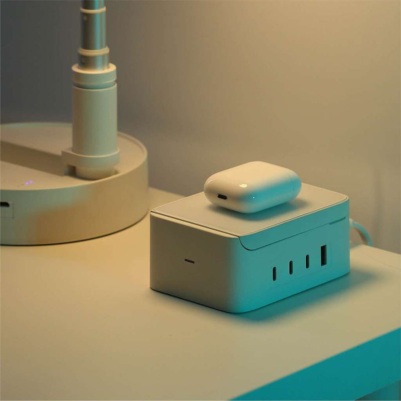 A White Spruce wirelessly charging Gen. 2 AirPods on a White Desk next to a White Smart Lamp