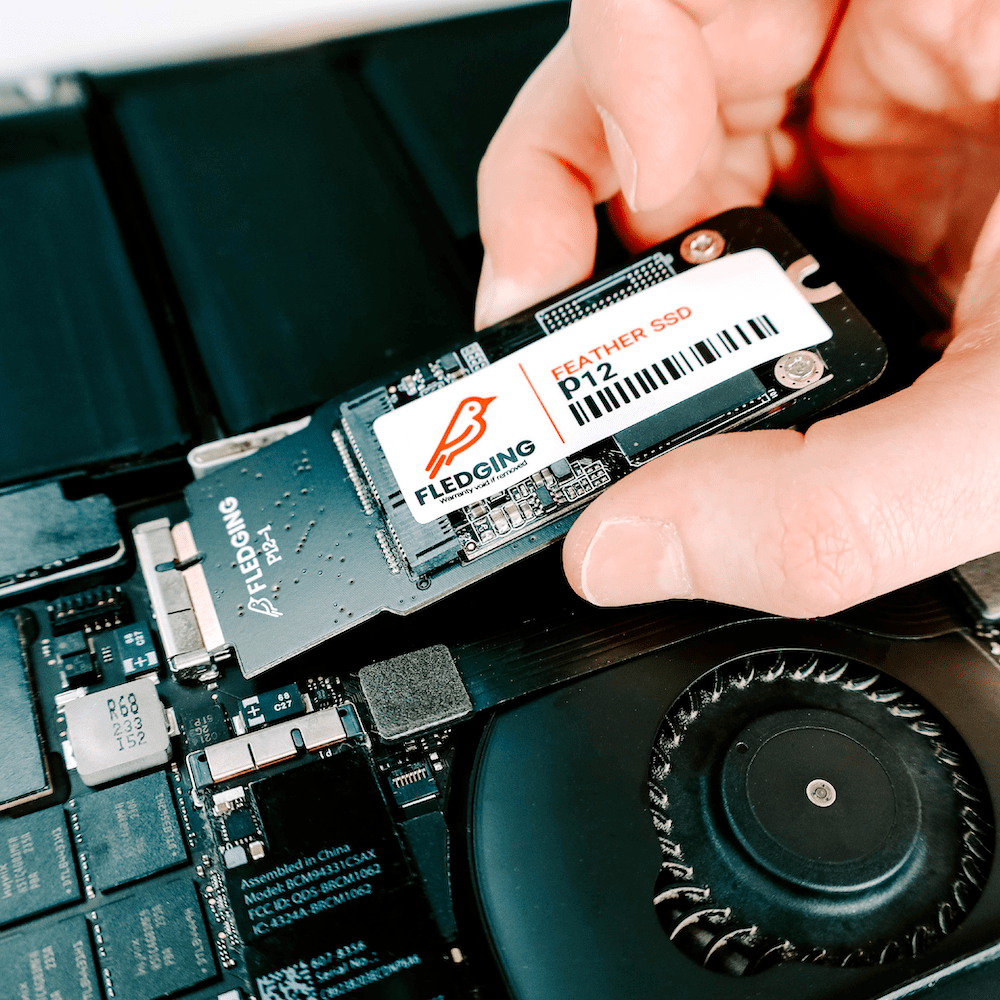 P12 Feather SSD getting pushed into the SSD port of an opened MacBook
