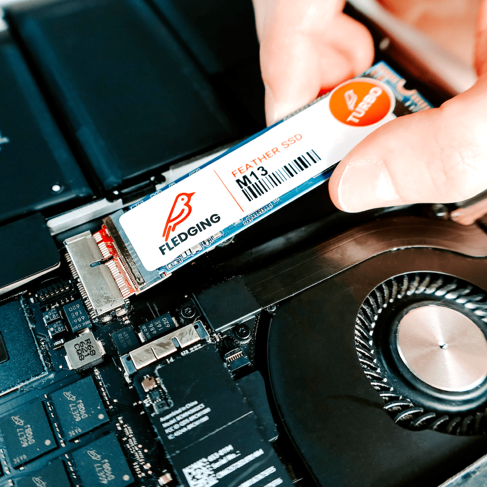 M13 Turbo Feather SSD getting pushed into the SSD port of an opened MacBook