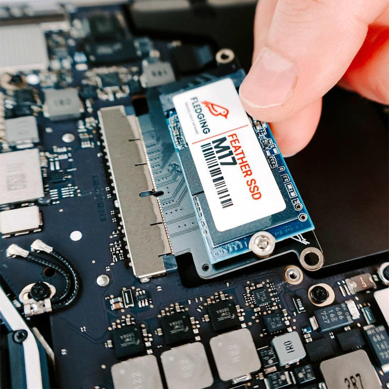 M17 Feather SSD getting pushed into the SSD port of an opened MacBook